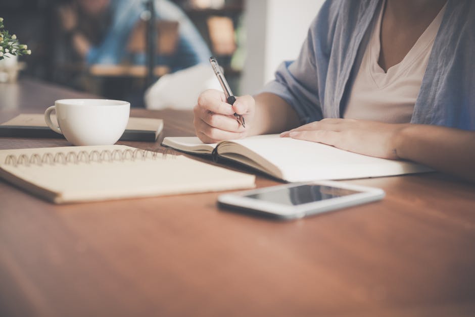 pexels photo 733856 733856 A woman writes in a notebook at a café table with a coffee and smartphone nearby.